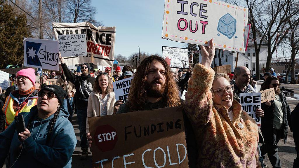 protesters hold up signs demanding ICE out of Minnesota