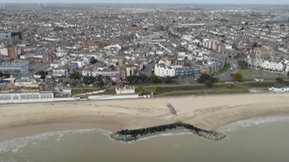 A drone view of a beach from above. You can see the beach and the city in the shot as well