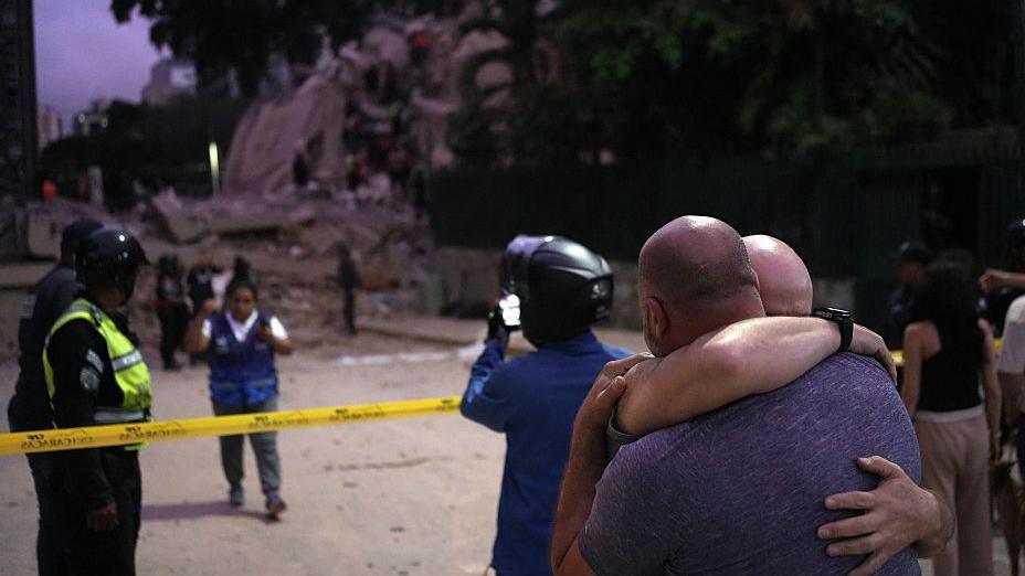 Men hug in front of a collapsed building following an earthquake in Caracas on June 24, 2026
