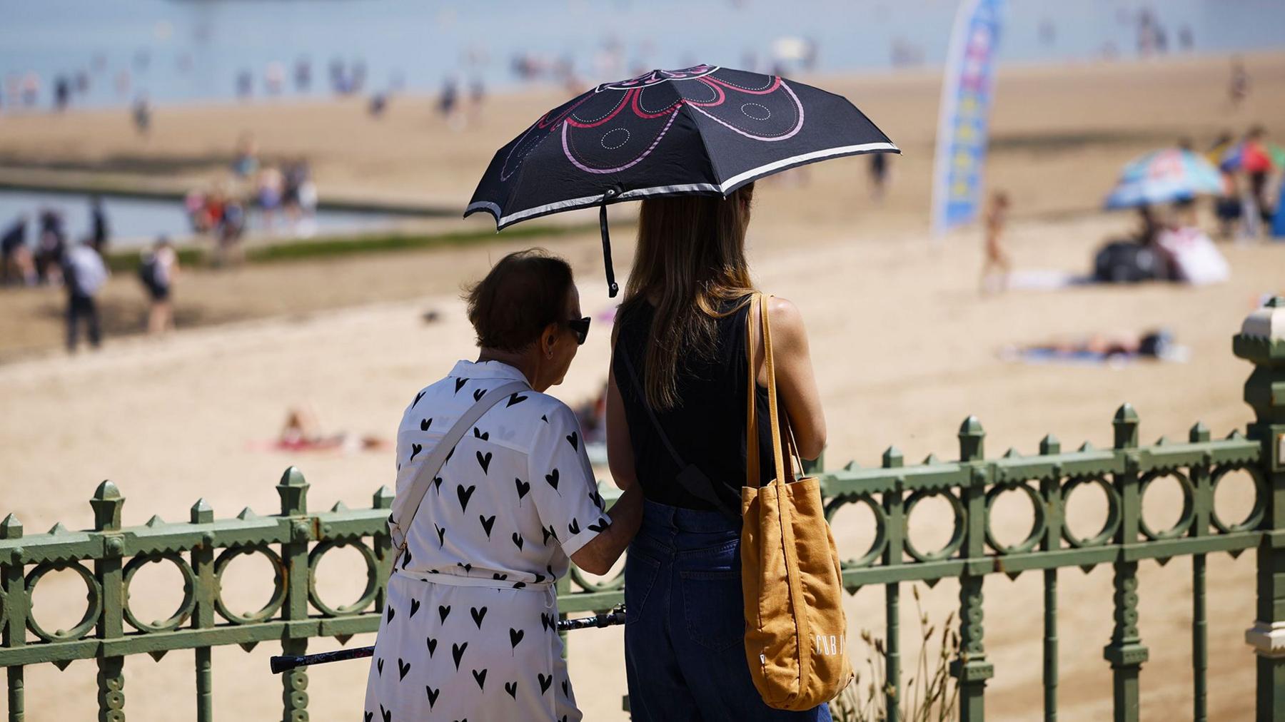 People use an umbrella to shelter from the sun on Margate Main Sands Beach as the UK is set to experience its hottest June day