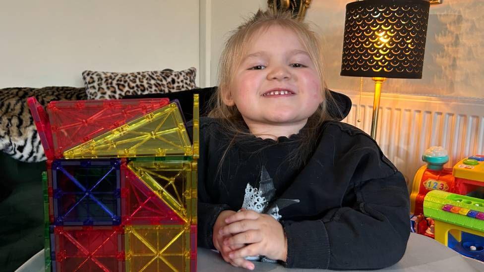 Dani-Rae Brown sat at a table with her elbow on the table. To her right is a multi-coloured plastic cube.