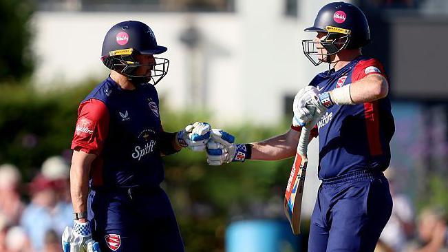 Batters Sam Billings and Harry Finch in all blue Kent kits touch gloves