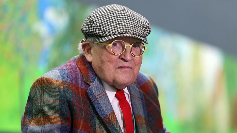 British painter David Hockney poses at the Orangerie museum in Paris, on October 7, 2021, in front of his painting "A year in Normandy", a 91-meter-long artwork painted during the lockdown in 2020. - Hockney made a hundred drawings on iPad in a matter of weeks and captured the effects of light and climate change during the four seasons.