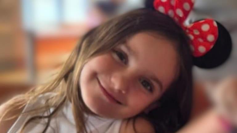 Aria Thorpe. She has long dark hair and is wearing Minnie Mouse ears. Her head is tilted to the side and she is looking ahead and smiling.