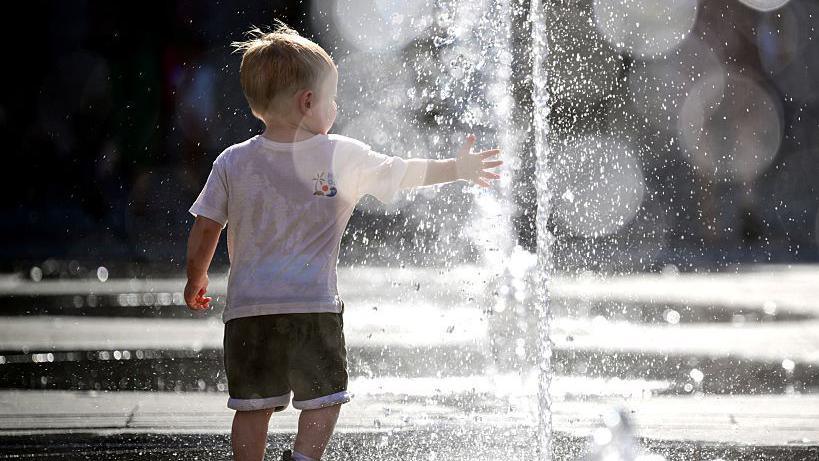A child, in a white T-shirt and black shorts, plays in a fountain during a heatwave in Lyon, south-eastern France on 18 June 2026