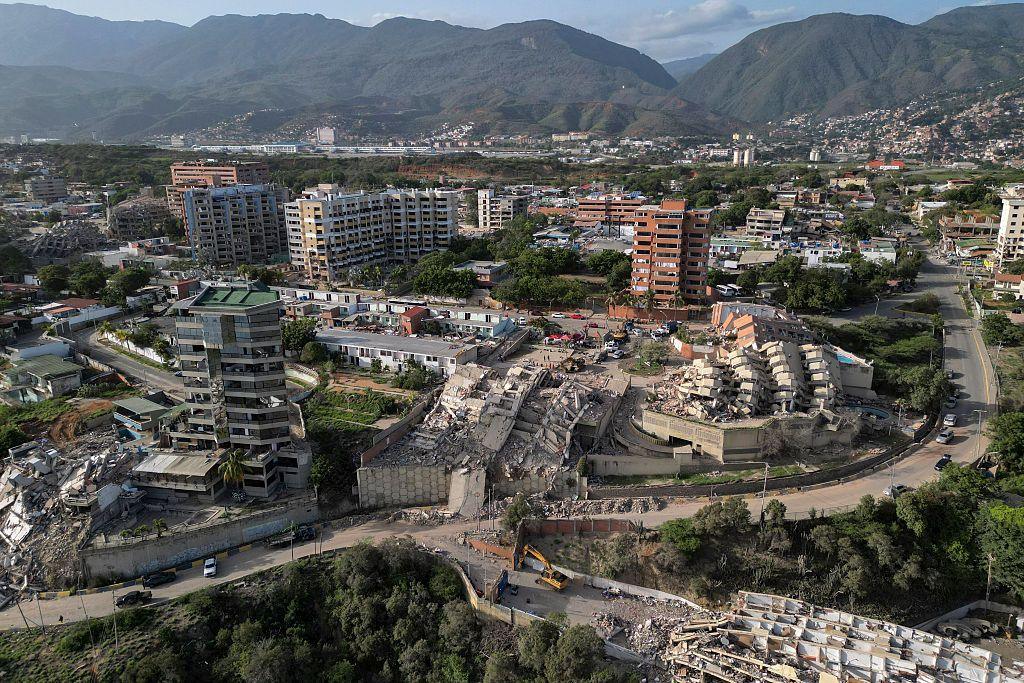 This aerial view shows collapsed buildings in Catia La Mar, La Guaira state, Venezuela, shows multiple collapsed buildings and rubble sitting in a valley with a backdrop of green mountains