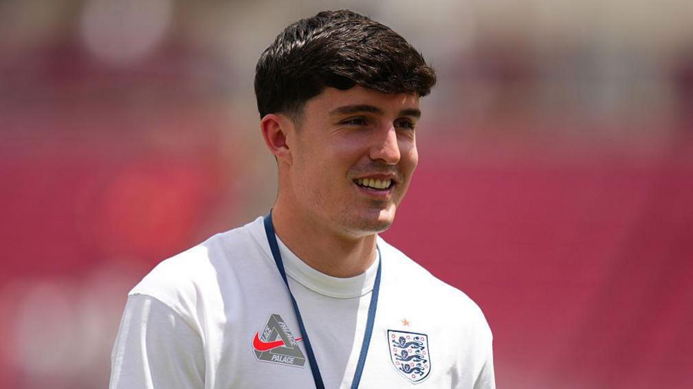 Tino Livramento, wearing a white England T-shirt, pictured smiling