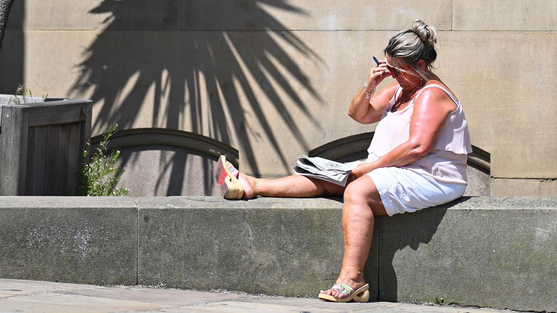 A crossword is worked on in the sunshine in the town centre in Huddersfield in Northern England on June 23, 2026, as temperatures increase to heatwave levels and are set to rise further in the week ahead.