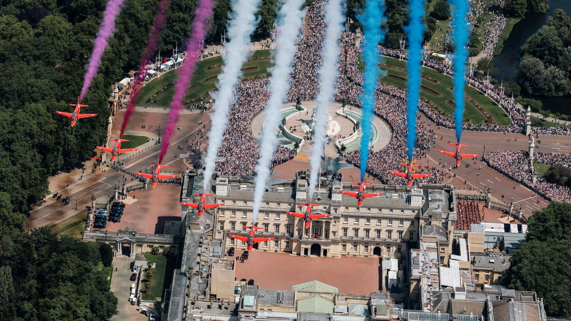 View from above as nine Red Arrows jets fly over Buckingham Palace trailing red, white and blue smoke behind them