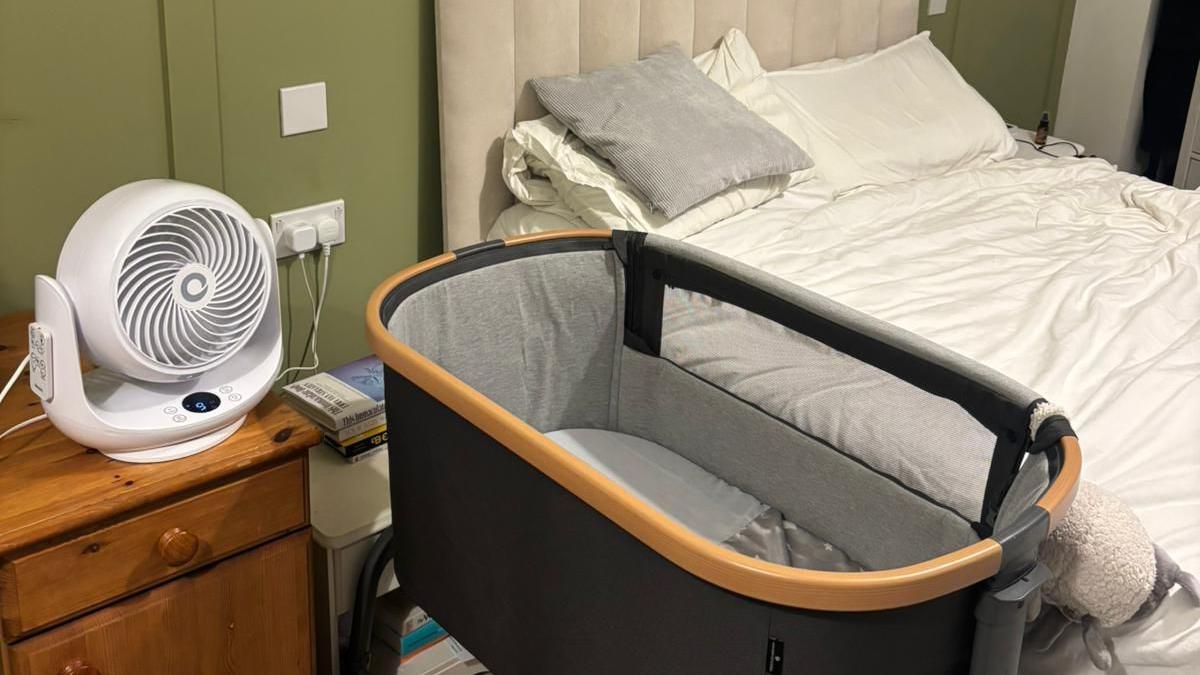 A bedroom with a bed, crib and a fan