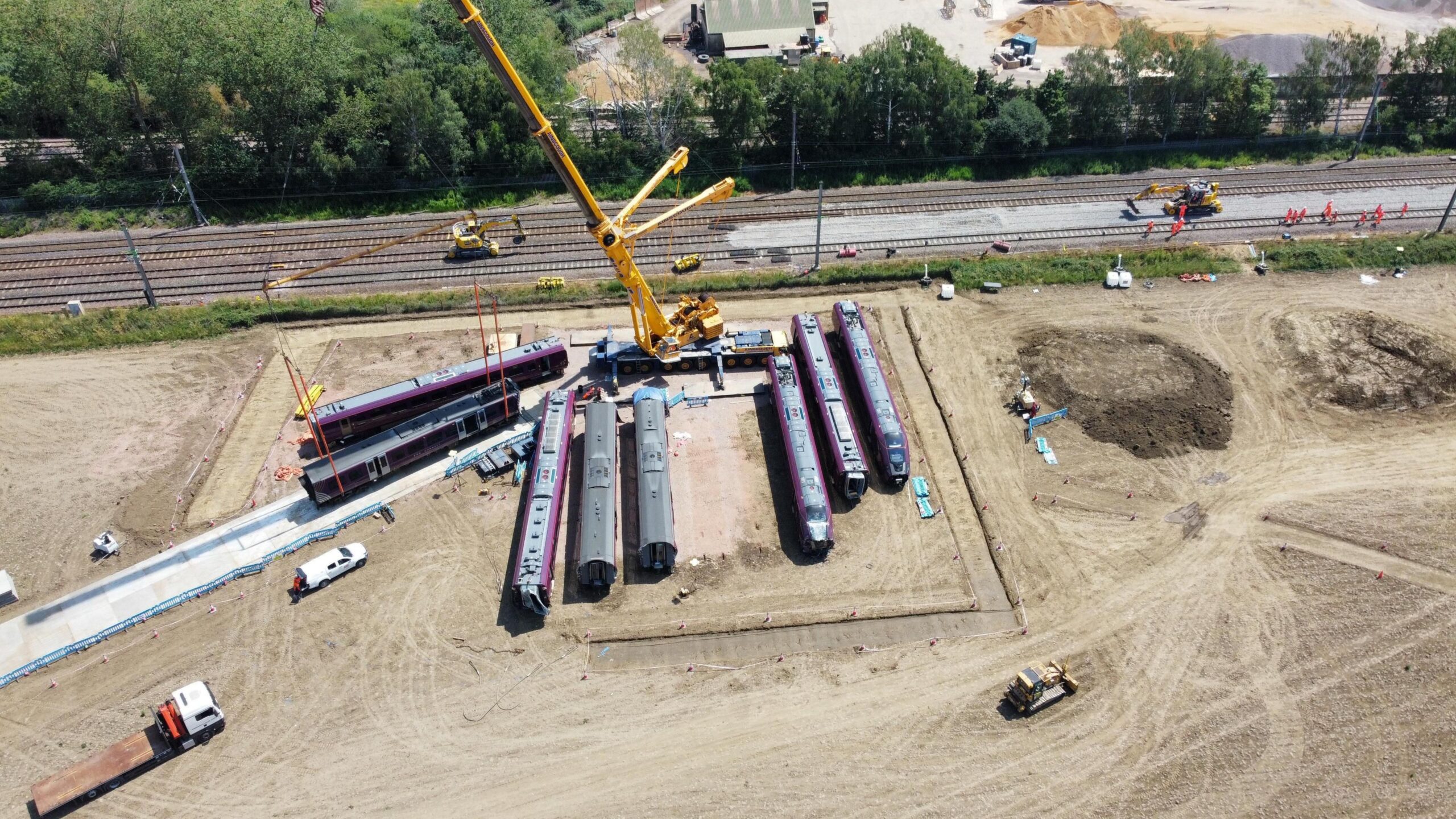 Train carriages on a piece of land next to a railway, with a couple being moved on to a make shift road