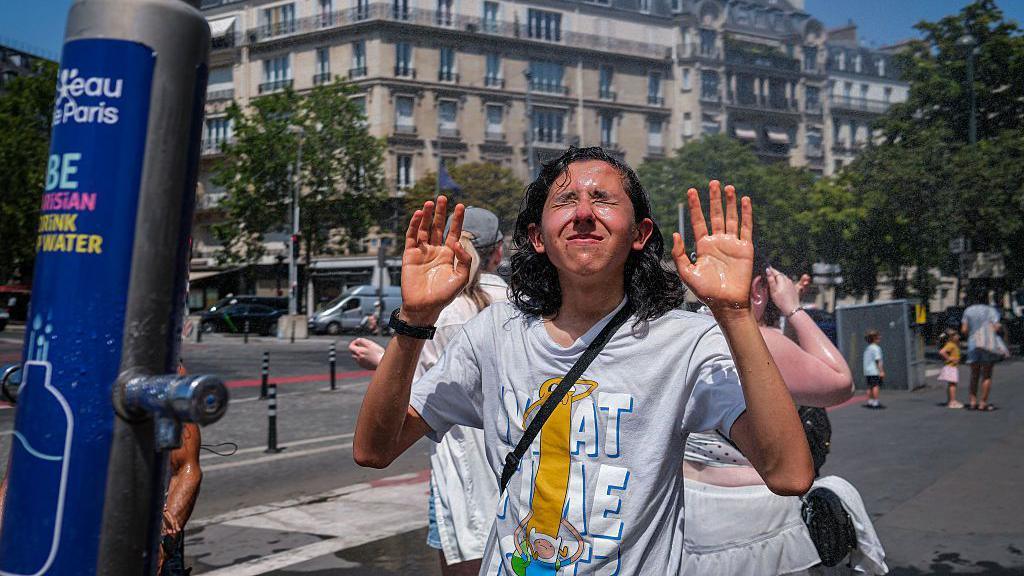 People cool off beneath a misting station during hot weather on June 24, 2026 in Paris, France.