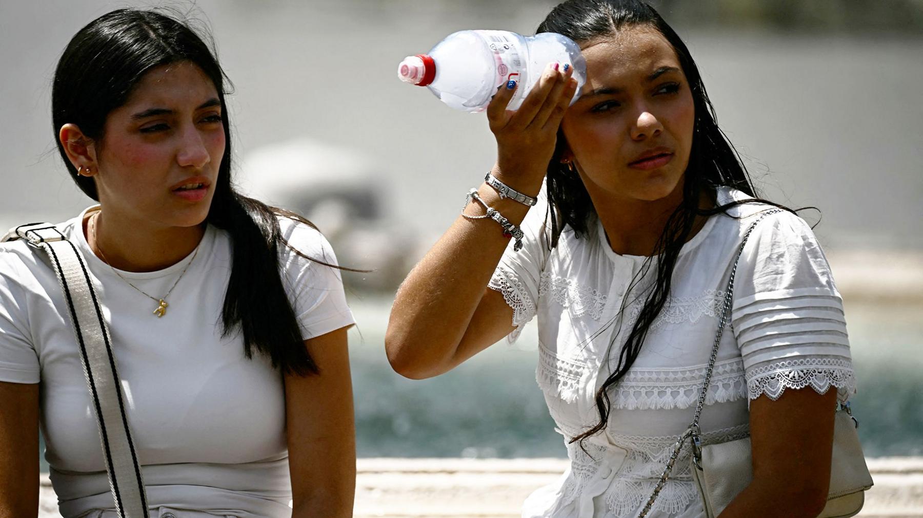 A woman places a bottle filled with ice on her head to cool down at St Peter's Square in the Vatican
