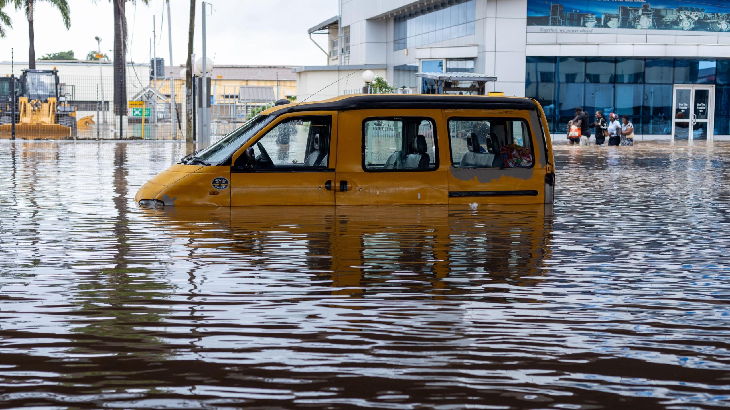 A yellow van half-submerged in floodwater