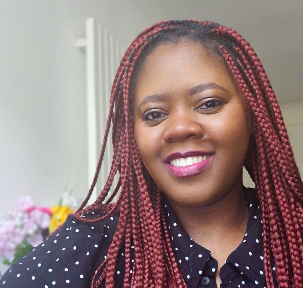 Chy, a 33-year-old woman, smiles in a close up photo. She had red braids and is wearing lipstick and smiling.