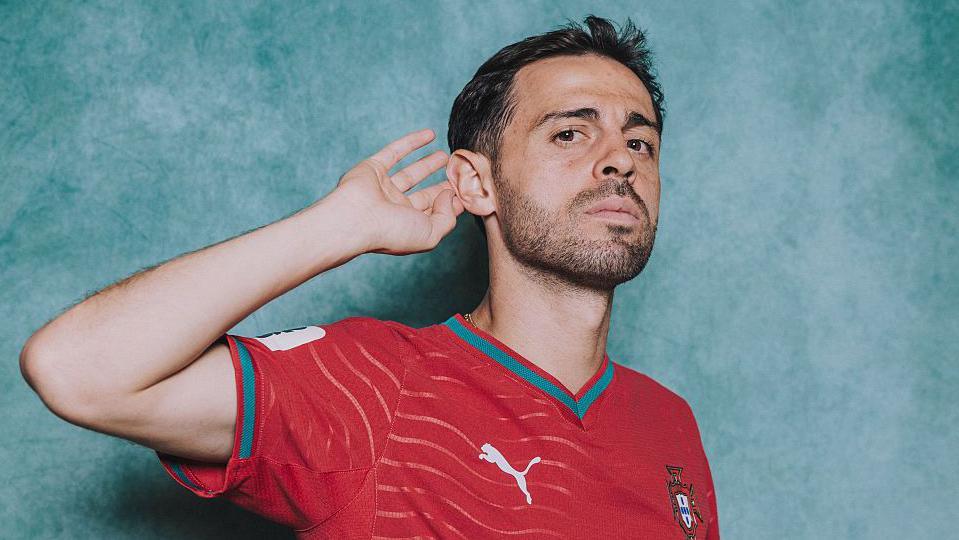 Bernado Silva cups his ear posing for a picture in a Portugal kit