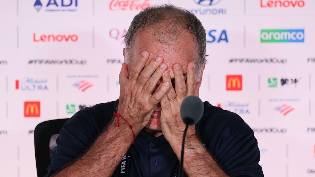 Marcelo Bielsa holds his head in his hands during a media conference after Uruguay's 1-0 defeat by Spain
