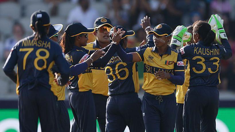 Sri Lanka's players, wearing dark blue and yellow shirts and blue trousers, exchange high fives to celebrate a wicket