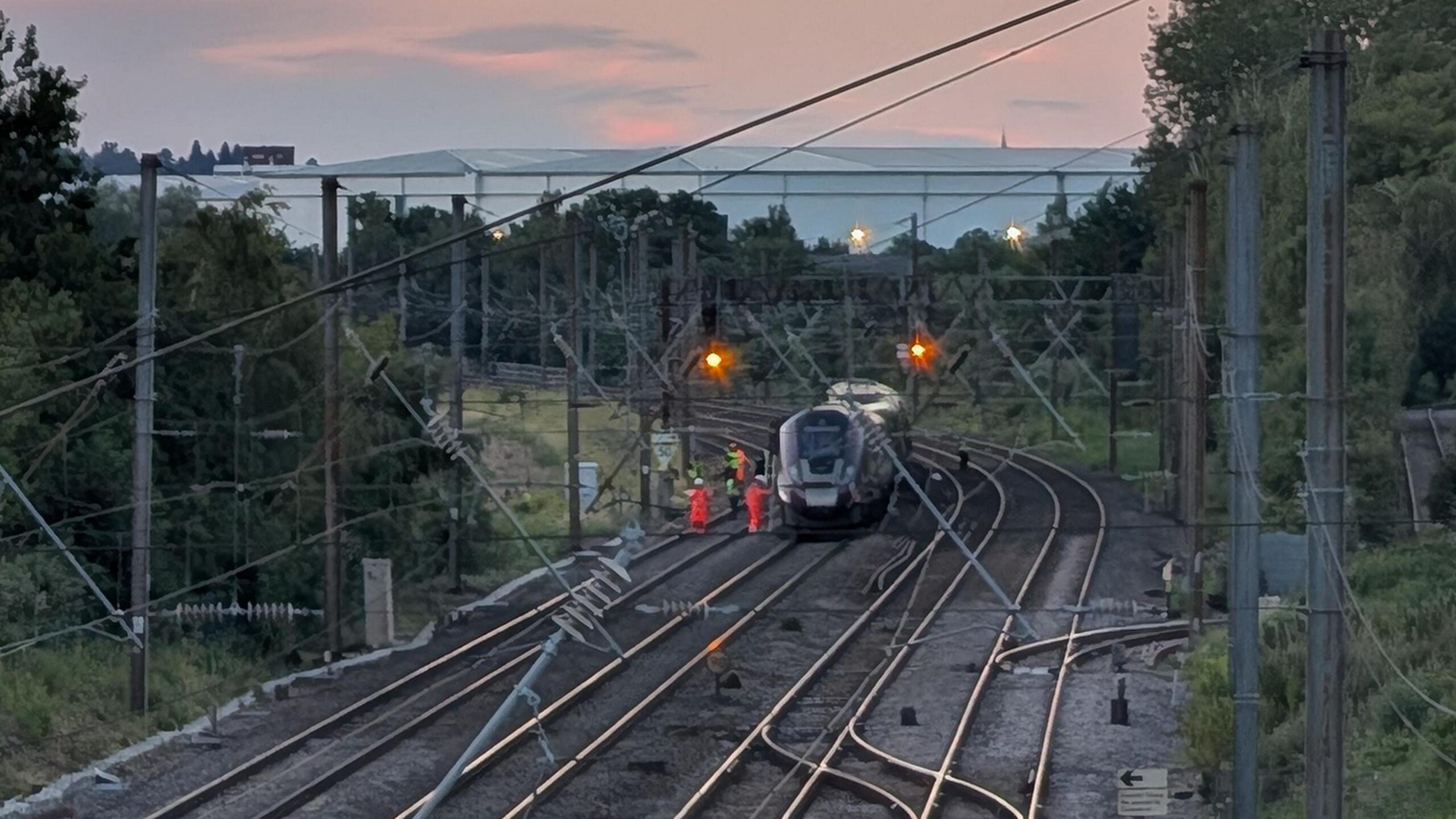 A train on tracks with workers around it as the light fades on Friday night.