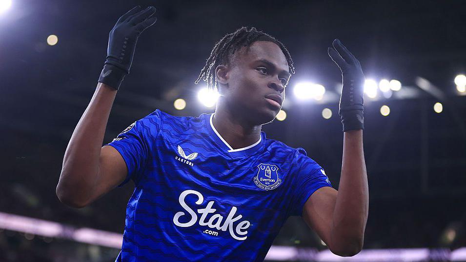 Tyrique George throws his arms up in the air while playing for Everton