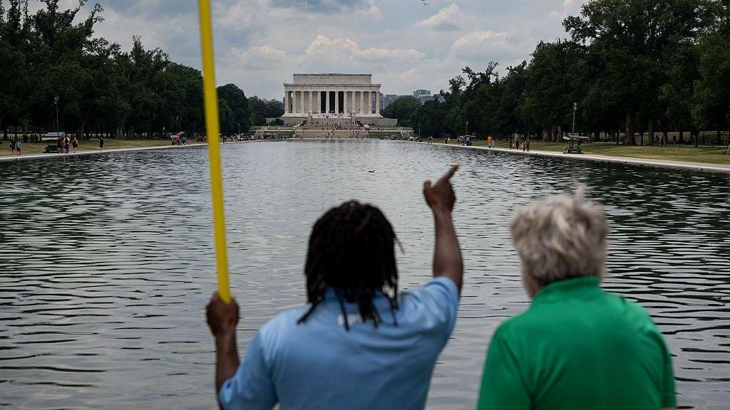 A worker provides a visitor with directions as he cleans the waters of the Lincoln Memorial Reflecting Pool following the completion of recent renovations in Washington, DC, on June 22, 2026.