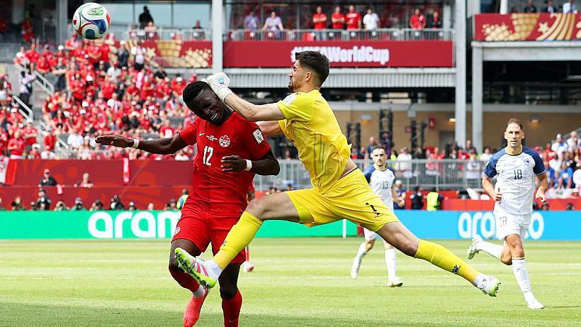 Bosnia goalkeeper Nikola Vasilj collides with Canada striker Tani Oluwaseyi.