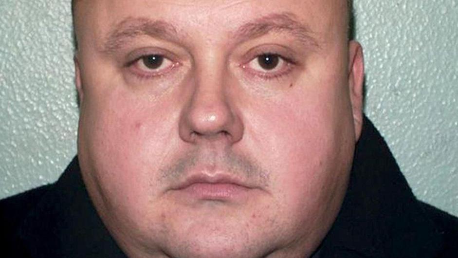 A mugshot of a fat man with stubble on his face wearing a black hoodie and looking directly into the camera with a neutral expression.