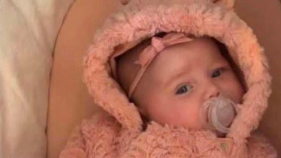 Dahlia-Rose Gartshore, a baby girl with a dummy in her mouth wearing a pink romper suit