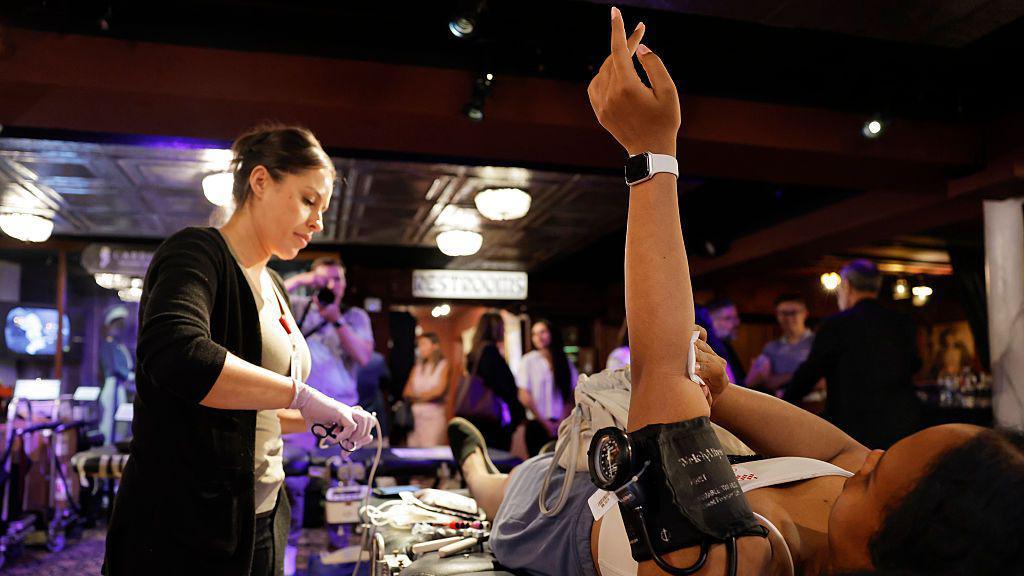 Woman holds hand in the air following blood donation