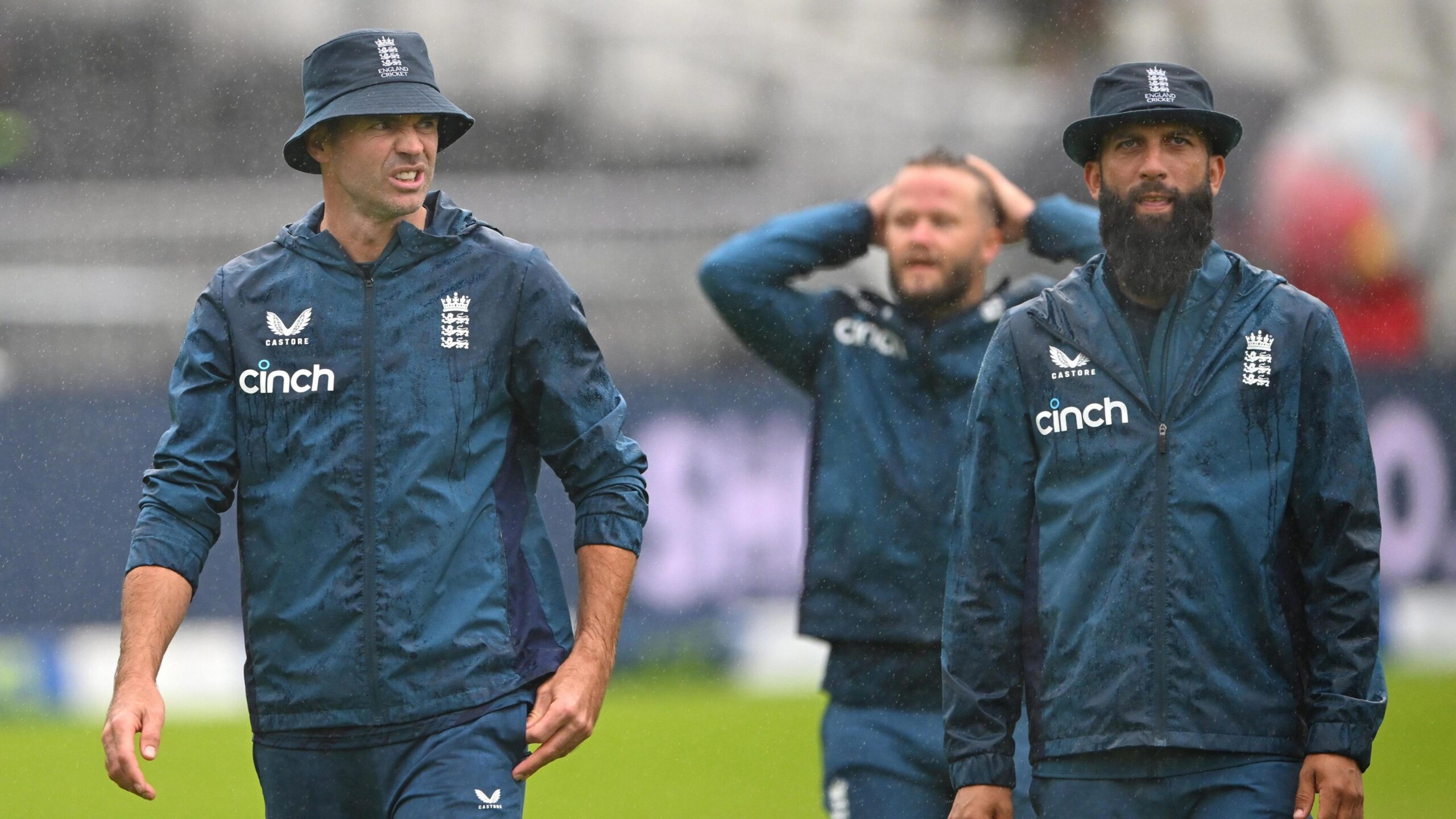 England's James Anderson, Ben Duckett and Moeen Ali in the rain on day five of the Ashes Test at Old Trafford in 2023
