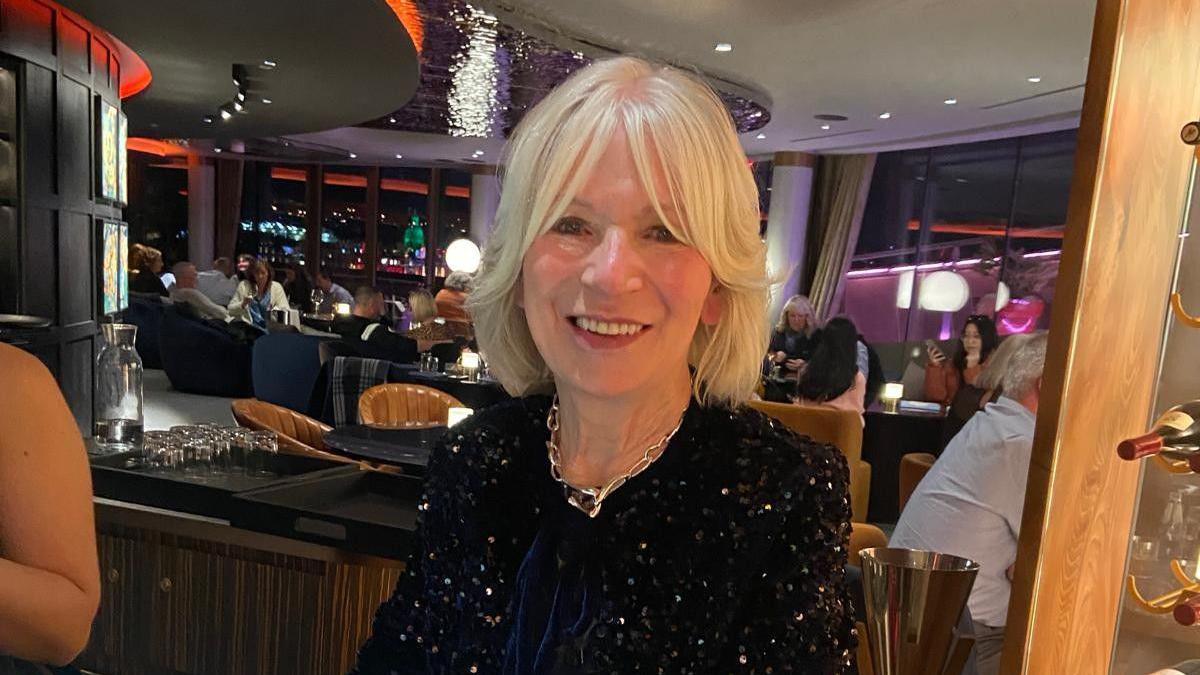 Violet Black sitting in a restaurant in a sparkly top