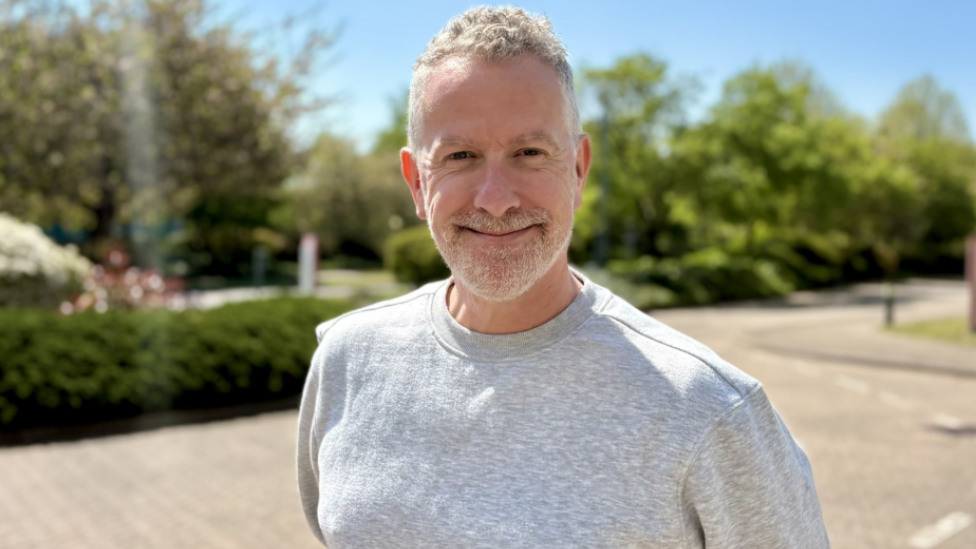 A man stood outside smiling into the camera