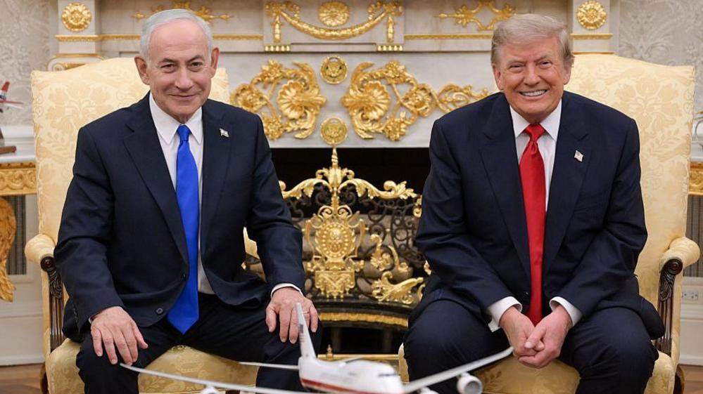 Netanyahu and Trump smile towards the camera during their meeting at the White House