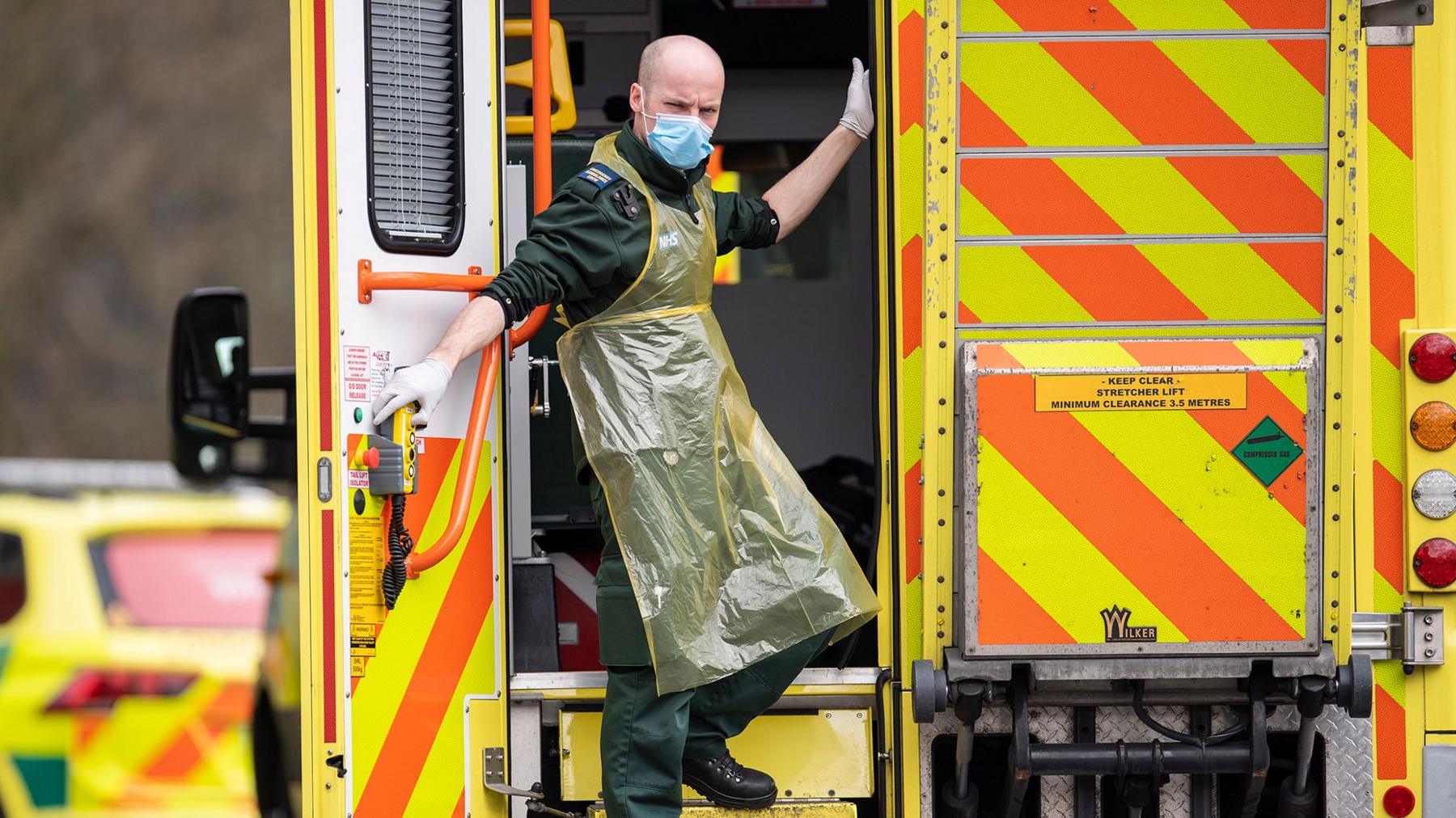 Paramedic in mask and PPE on back of ambulance