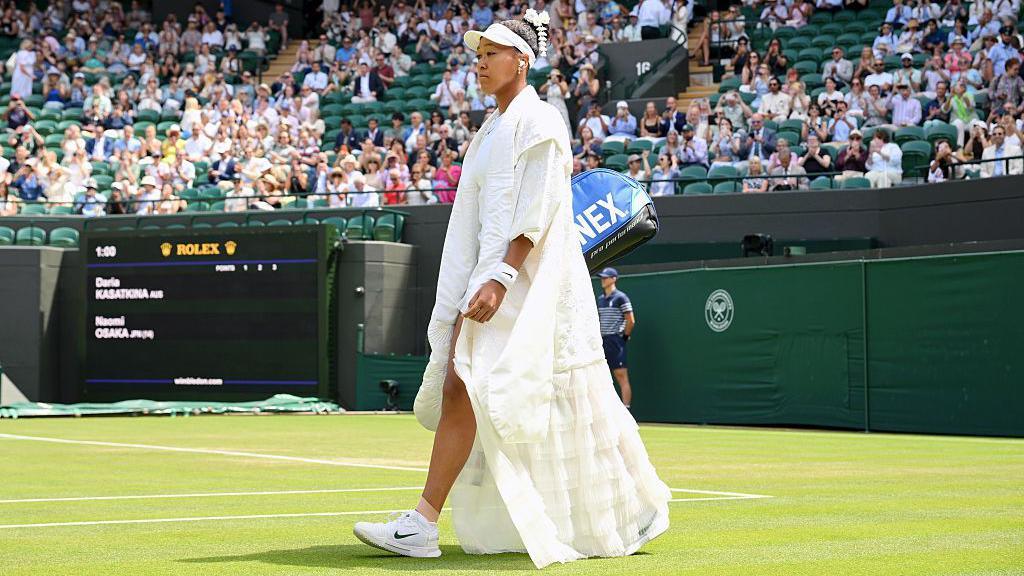 Naomi Osaka walks out to Court One dressed in a floating robe