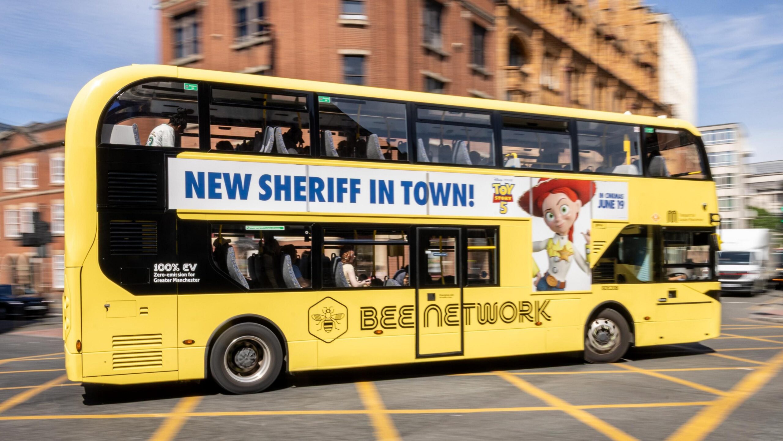 Yellow Bee Network bus in central Manchester sports an advert on the side for Toy Story 5. It contains the slogan "NEW SHERIFF IN TOWN!" as a pun for the Greater Manchester mayoral election.