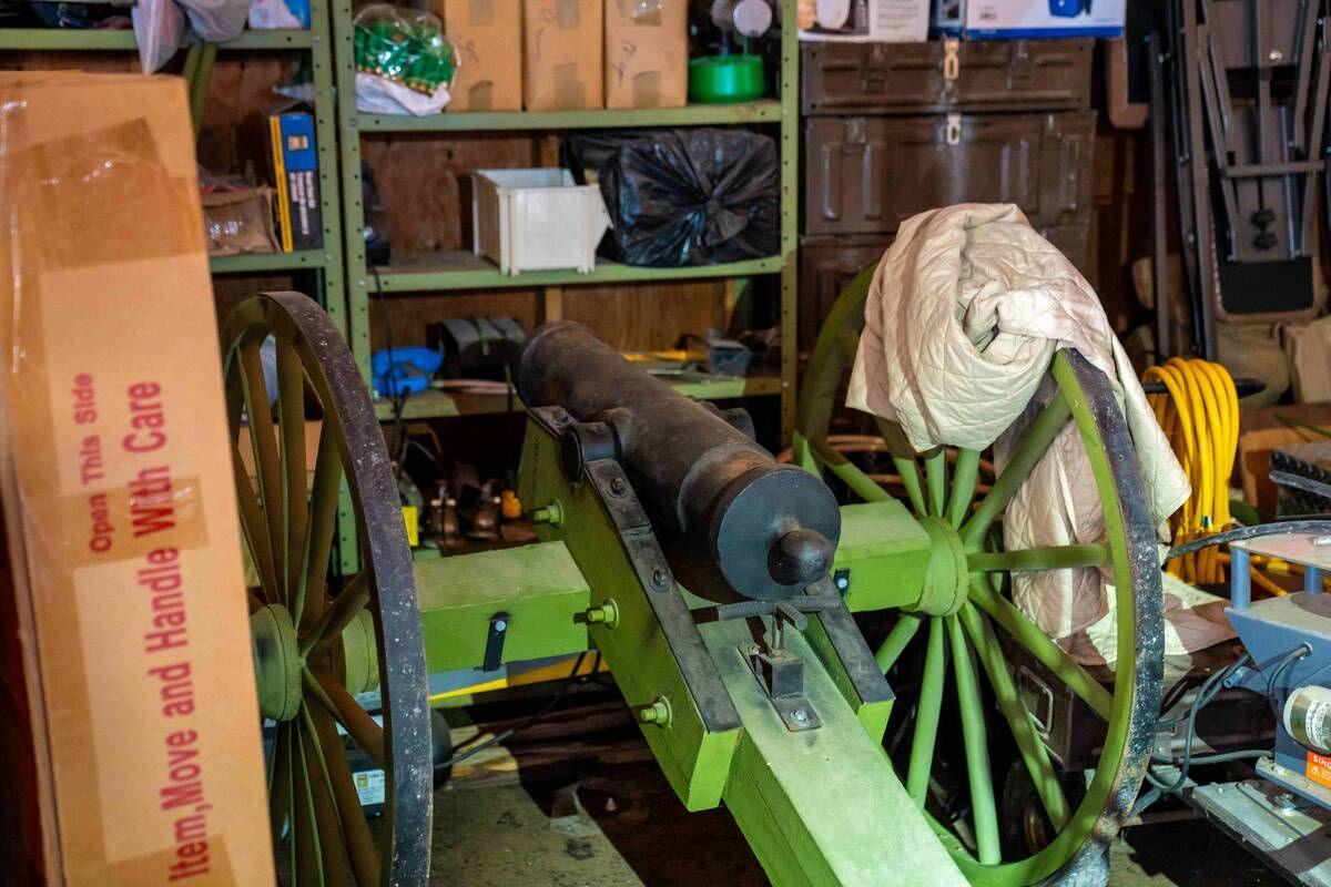 An antique cannon is seen in a storage area with shelving units and other boxes and miscellaneous items in a home in Dauphin, Manitoba.
