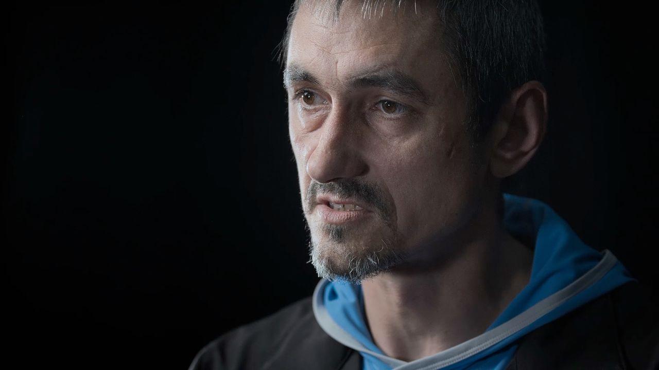 Portrait image of Oleksii Sivak, who has a short beard and moustache, looking to the left of the camera, wearing a light blue hoodie under a black jacket