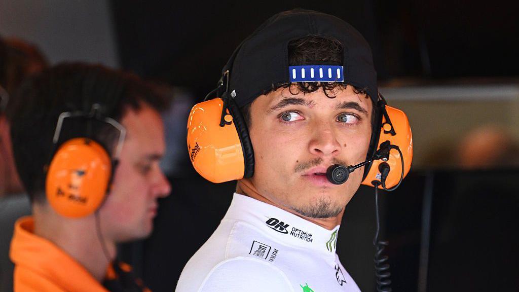 Lando Norris wears headphones in the McLaren garage