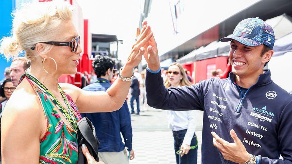 British actress and singer Hannah Waddingham high-fiving Williams driver Alex Albon in the paddock