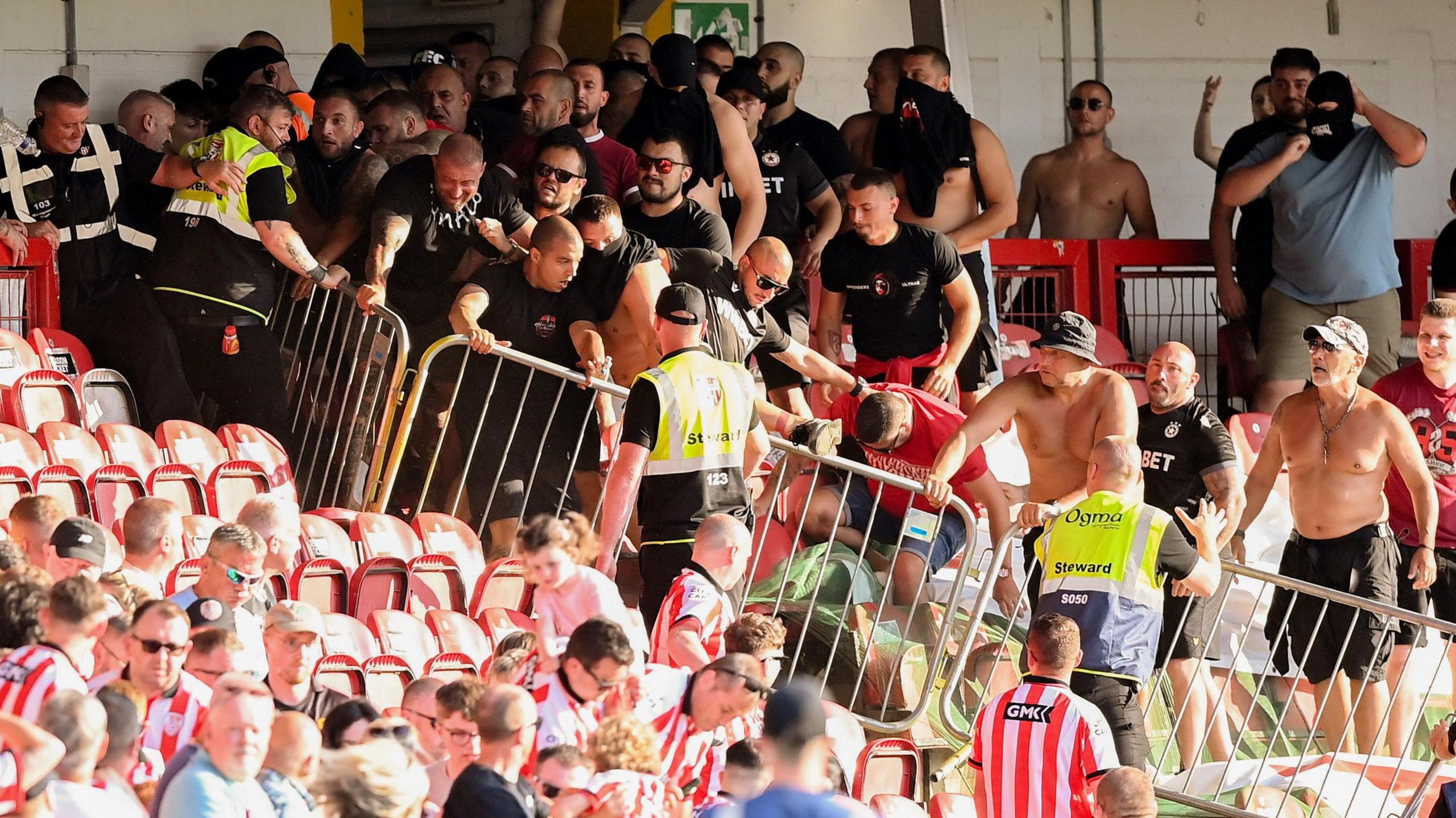 Shows football fans in a stadium separated by barriers