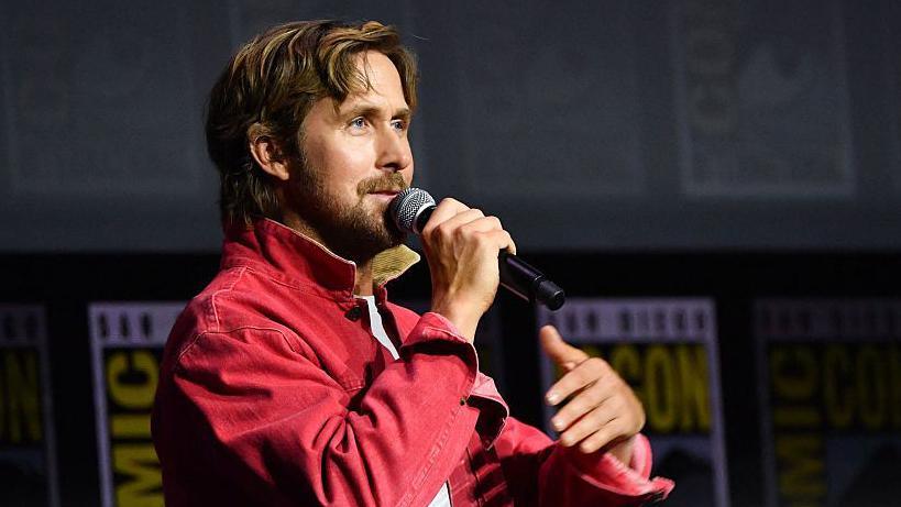 Ryan Gosling speaking into microphone on stage at San Diego Comic-Con