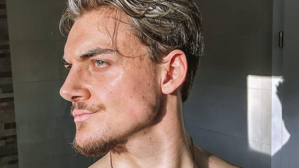 Marvin, a young man looking to the side with a defined jaw, wavy hair and some facial hair