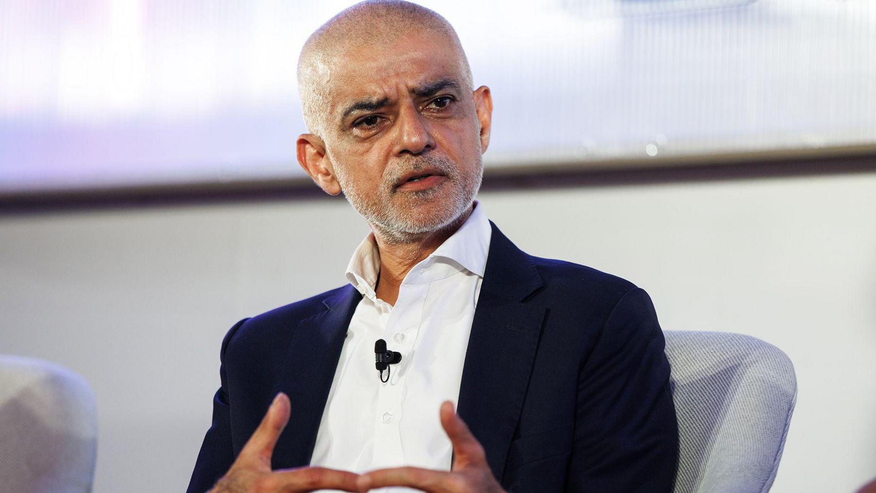 Sadiq Khan sitting in a light grey chair wearing a dark suit and a white shirt.