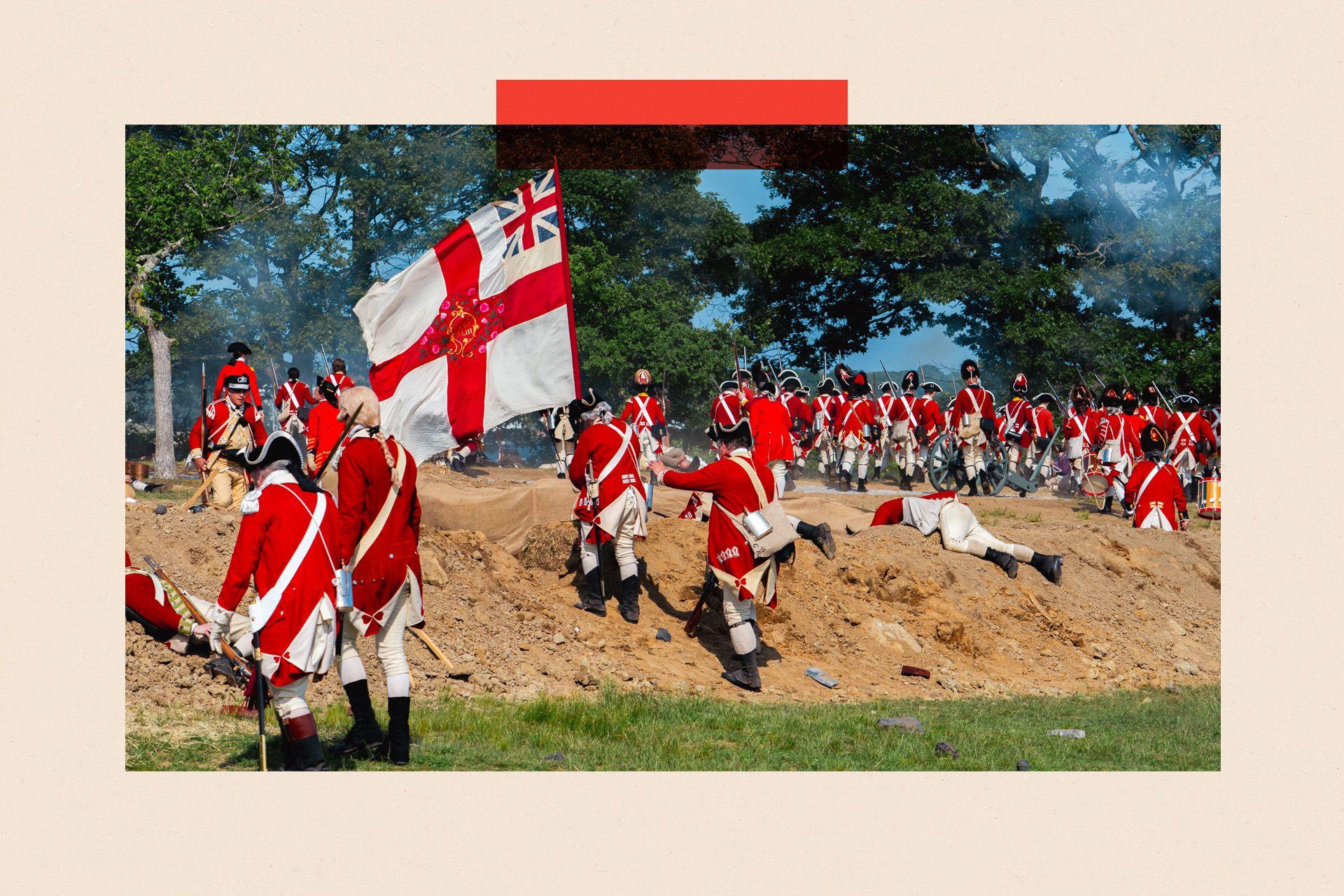 A group of men wearing red and white uniforms climb a sandbank as part of a battle re-enactment