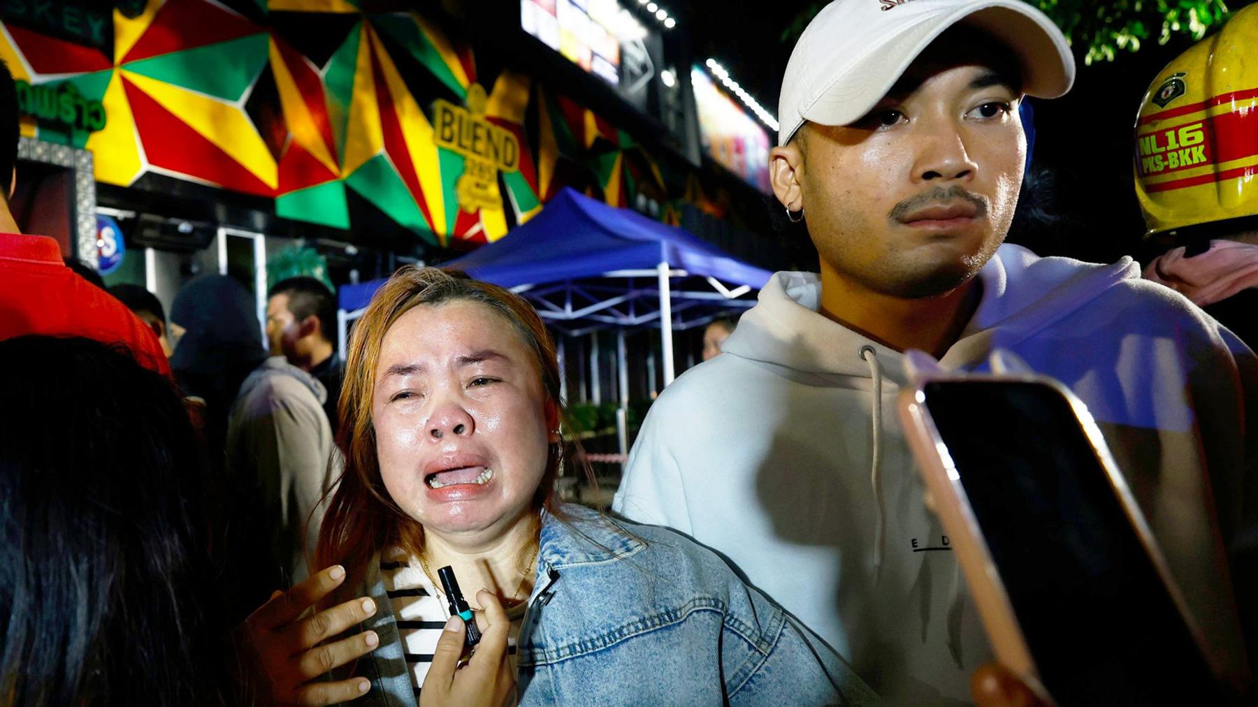 A relative of a victim in tears outside the bar in Bangkok that was hit by a fierce fire