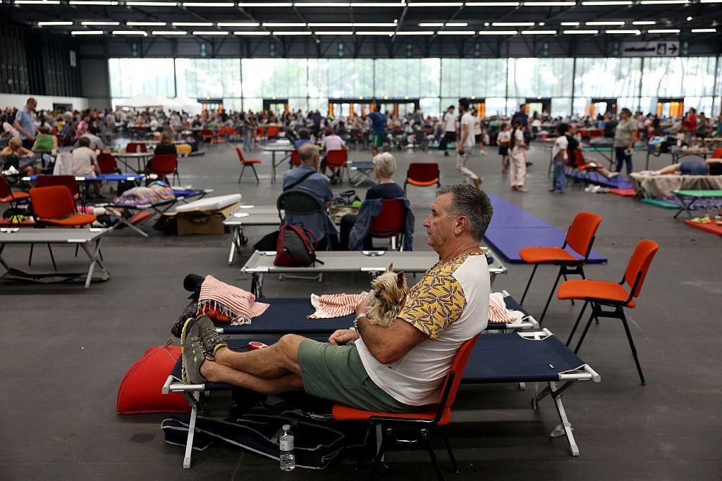 A man sits with his dog in an evacuation shelter in a gymnasium.