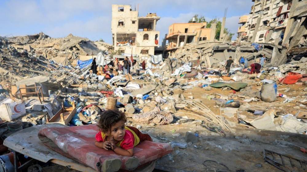 A Palestinian girl child lies on a damaged mattress in Gaza City