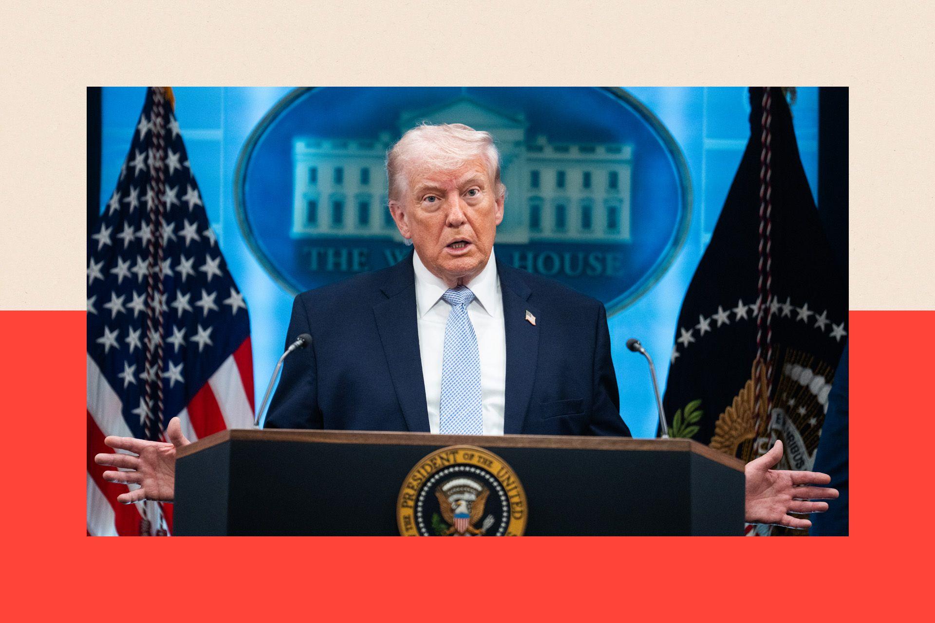 Donald Trump wearing a dark blue suit and a light blue tie standing behind a podium