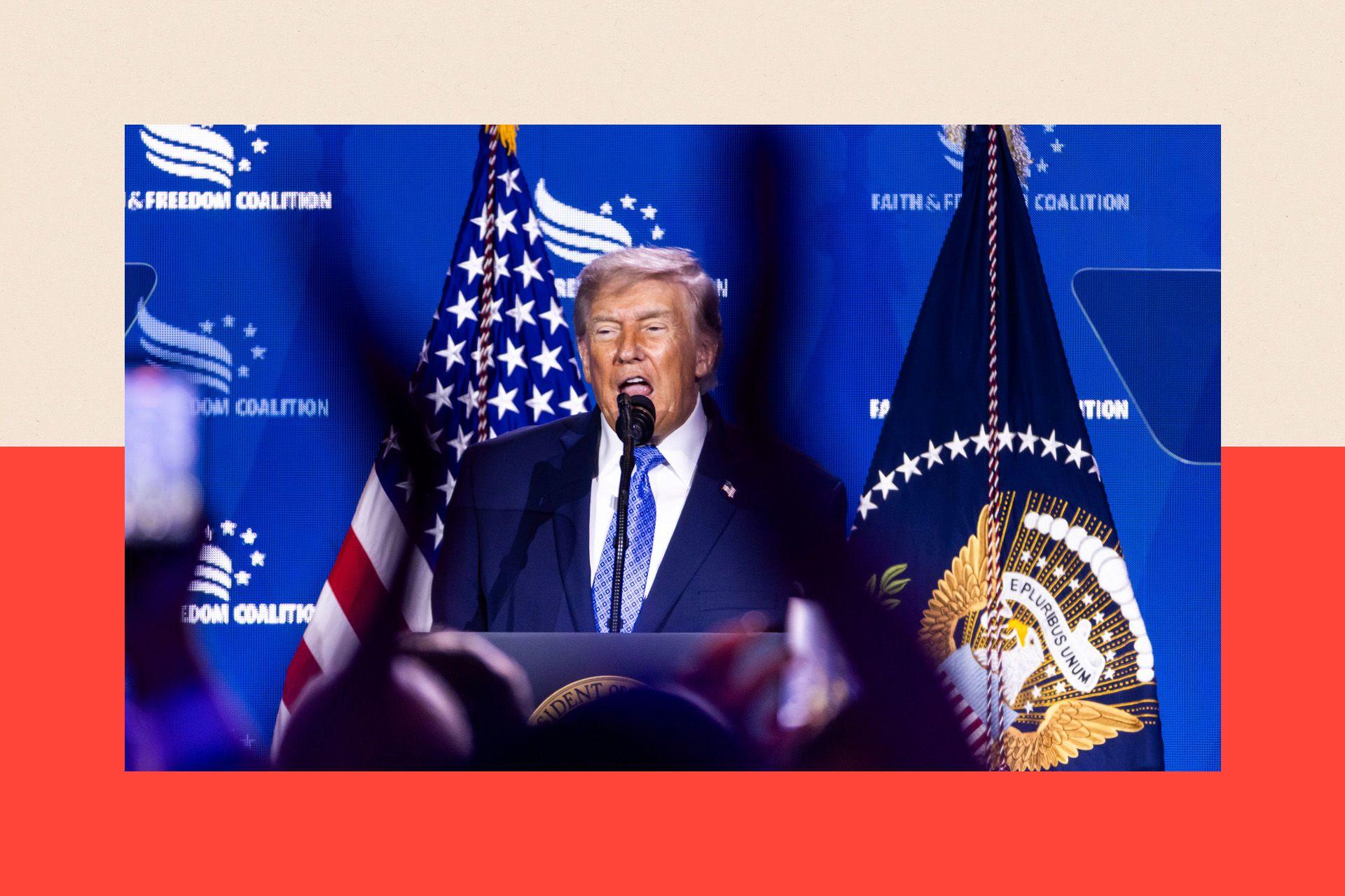 Donald Trump stands in front of a blue screen and flags